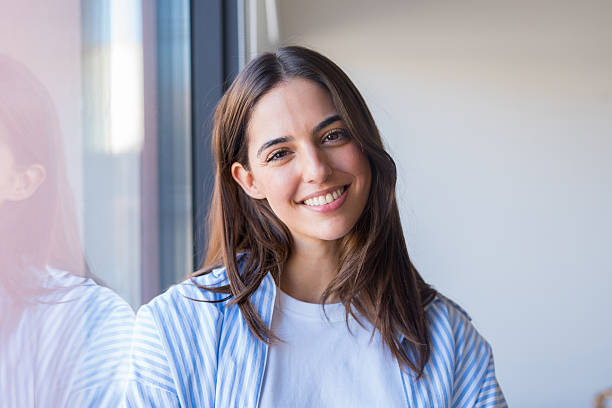 istock A positive young woman stands by a window smiling softly, captur 2260099115
