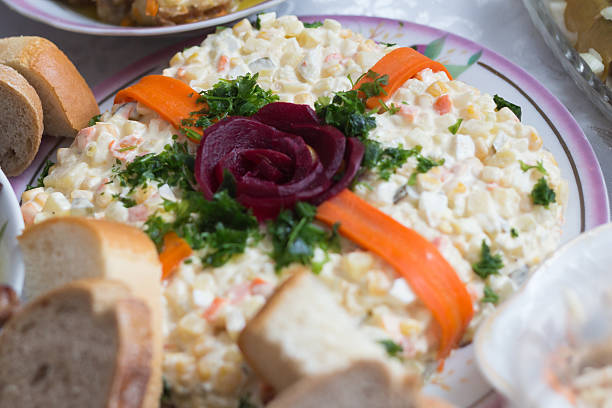 Close-up of a festive Russian salad (Olivier) artistically decorated with a carved beet rose, fresh parsley, and carrot strips. Served at a family dinner.