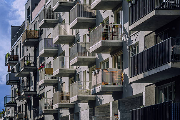Sturdy concrete balconies form a geometric facade on a contemporary Berlin residence. Sunlight and shadows create depth, while small plants and personal touches hint at urban living and community.
