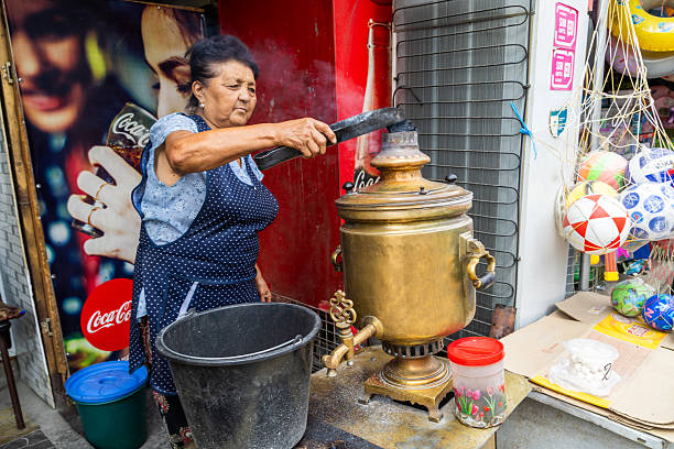 Elderly woman adding coal to samovar at roadside cafe in Cholok, Kyrgyzstan - July 16, 2024