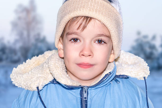a boy in a blue jacket and a beige winter hat