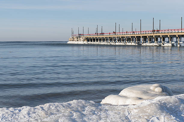 istock Sunny Winter Day at the Icy Pier with Distant Walkers 2260110988