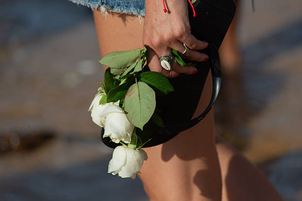 Detail of a worshipper carrying white flowers, highlighting a cowrie shell ring, on a religious festival day on the coast.