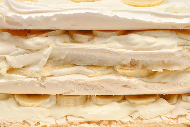 A detailed close up of a layered cake made of meringue whipped cream and fresh banana slices