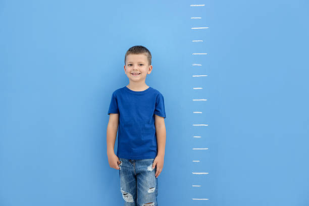 istock Little boy measuring his height near blue wall 2260124028