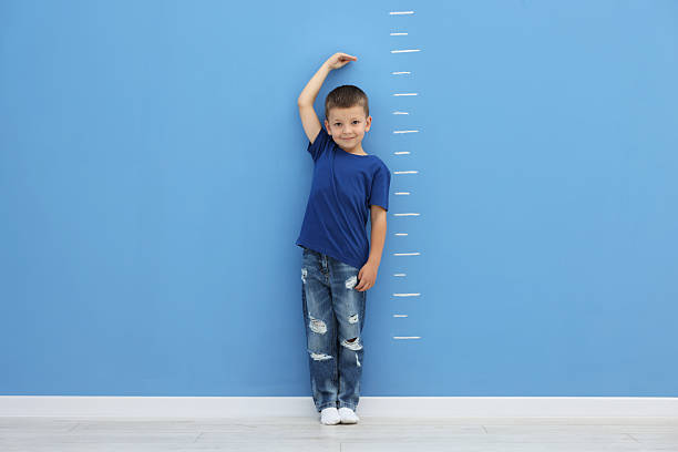 istock Little boy measuring his height near blue wall 2260124173
