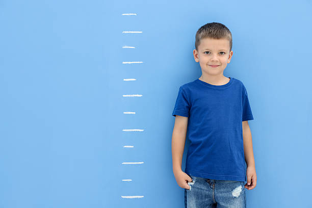 istock Little boy measuring his height near blue wall 2260124188