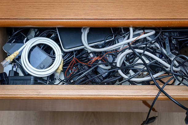 Messy household drawer showing old cables, phones, and power adapters creating electronic waste