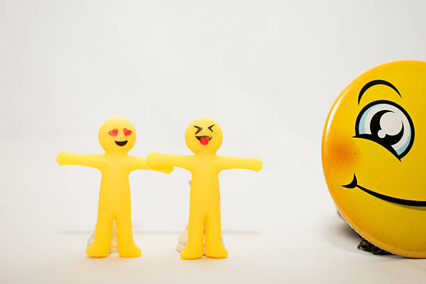 Conceptual image of yellow emoji-style figures representing teamwork, collaboration and social interaction. Minimal composition on white background illustrating cooperation, unity, inclusion and group dynamics. Ideal for business, education, social themes, leadership and communication concepts.