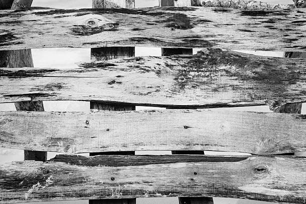 A detailed black and white, close-up view of rough, weathered wooden planks, ideal for backgrounds, nature, and environmental themes, promoting sustainability and design.