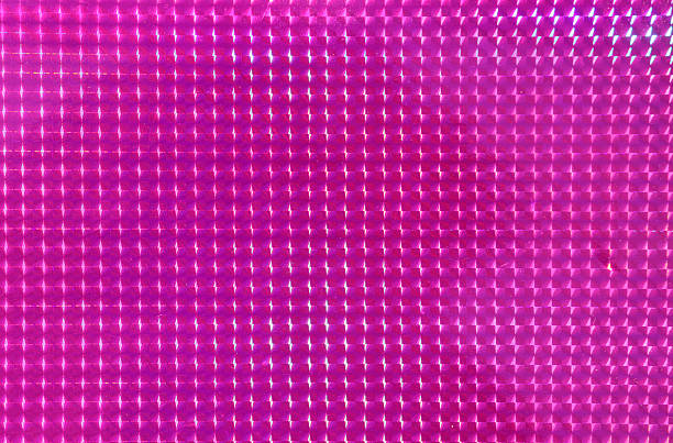 Shimmering pink geometric surface with faceted square patterns creating a reflective, textured grid background