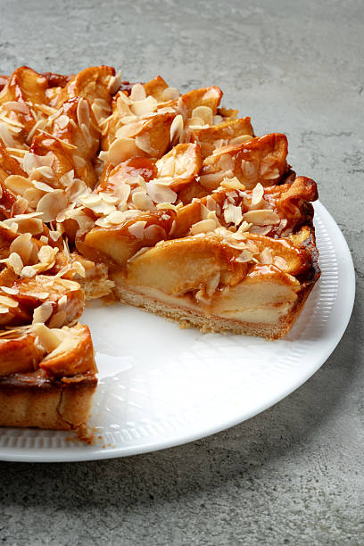 Delicious apple tart with almond topping on a white plate in a kitchen setting