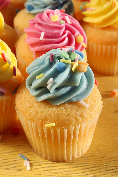 Stock photo shows homemade Easter cupcakes, cakes, and muffins in pastel shades of blue, yellow, and pink, each decorated with smooth butter icing and colorful sprinkles. These baked treats create a festive, cheerful bakery displa