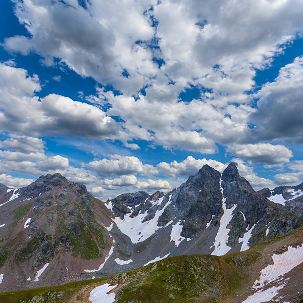green mountain chains in snow under a blue cloudy sky, mountain  travel scene