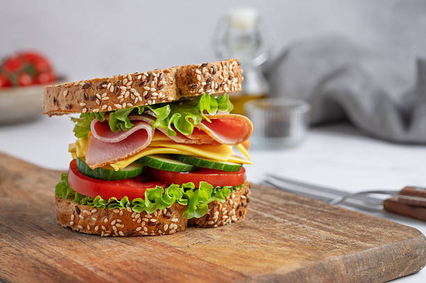 istock Sandwich with ham, cheese, lettuce, tomatoes, cucumbers and seeded bread on a wooden board 2260175634
