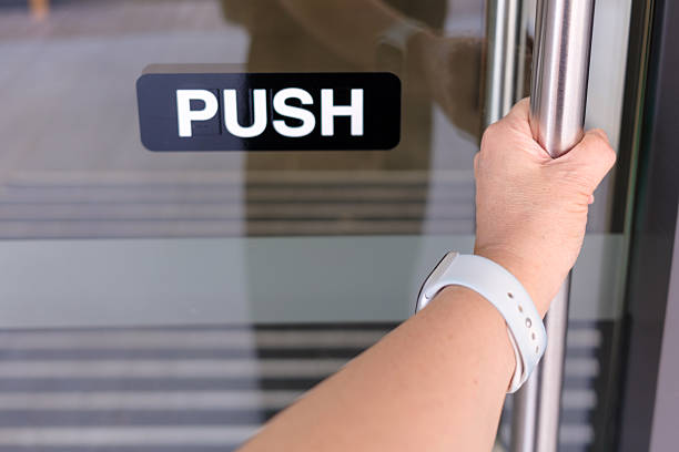Close Up of Person Opening Glass Door with Push Sign.