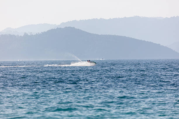 RC racing boat on straightaway skips across the water leaving behind huge spray and ripples.
