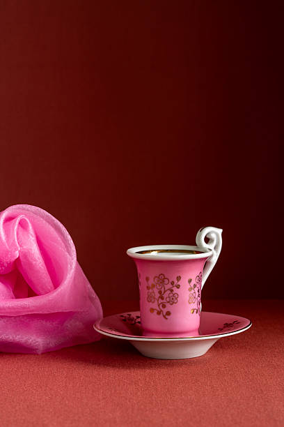 Still life with small pink cup and pink shawl on brown background. Minimal composition with cozy mood, soft colors, elegant decorative style.