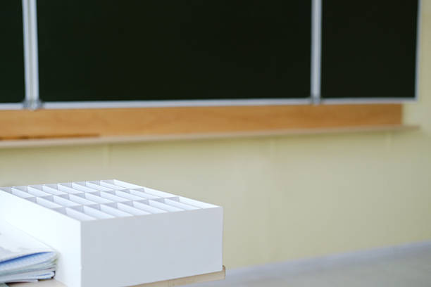 Teacher's desk in a classroom with a phone storage box, showcasing an organized space for learning, complemented by a chalkboard and educational resources for student engagement