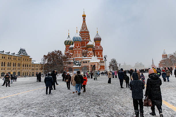 Moscow, Russian Federation - January 07, 2026: Snowy scene at Red Square featuring St. Basil's Cathedral, with numerous people walking on the cobblestone path