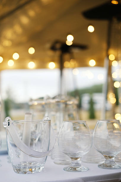 Beautifully arranged glassware on a table, illuminated by soft bokeh lights, enhancing the festive atmosphere for weddings or celebrations with copy space