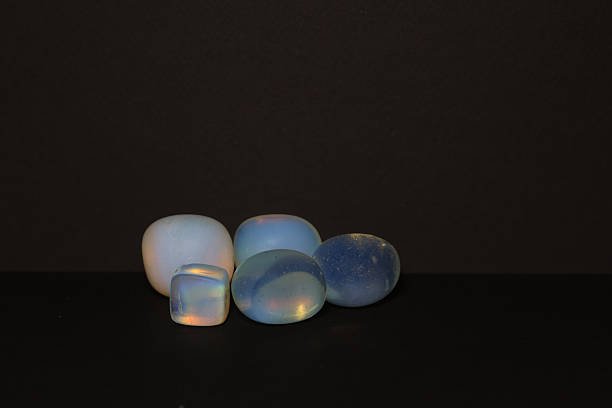 A group of smooth, polished opalite tumbled stones in various shapes and subtle iridescent hues.
