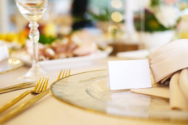 Beautifully arranged table setting with blank place cards on elegant plates, accompanied by gold cutlery and delicate floral decor, perfect for event planning mock up