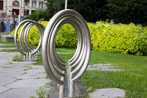 A close-up shot showcases a vibrant red bicycle parking rack fashioned into a creative metal sculpture. Situated in an urban park, it offers a convenient and stylish solution for cycle parking in