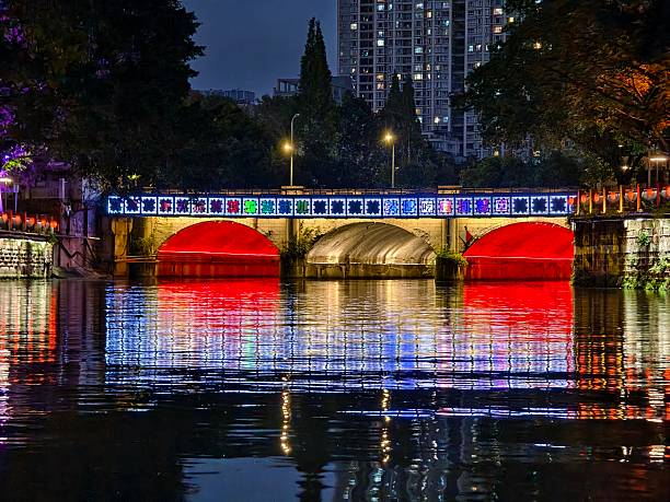 Illuminated bridge at night with colorful lights reflecting on water surface