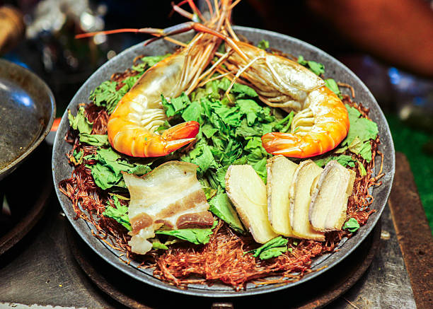 Top view of steamed prawns with vermicelli in a traditional Thai pot, showing authentic home style seafood and warm family dining culture.