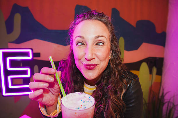 Woman making funny face drinking milkshake with milk mustache