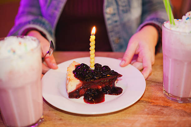 Person celebrating birthday with cheesecake and milkshake