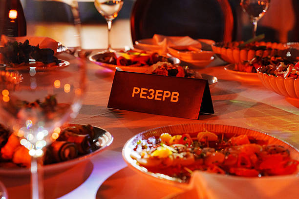 A table is arranged with various dishes and drinks. A sign indicates the table is reserved for guests. The setting suggests a special event at night.