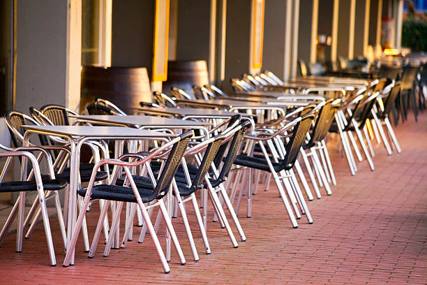 Row of empty tables, sidewalk cafe at dusk.  Mera beach  in Oleiros, Rías Altas, A Coruña province, Galicia, Spain .