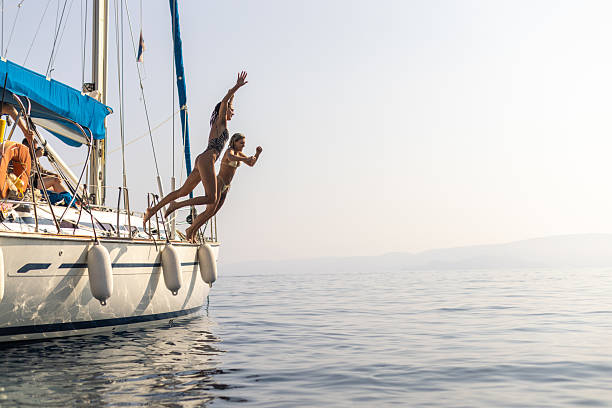 istock Beautiful women jumping into sea from a sailboat deck 2260222071