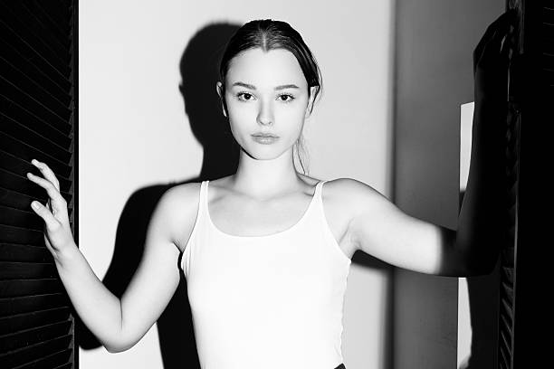 Woman posing in a studio with striking shadows creating contrast and minimalist aesthetics