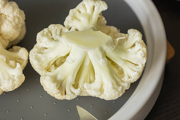 Person weighing cauliflower in a reusable paper bag on a scale at a local farmers market