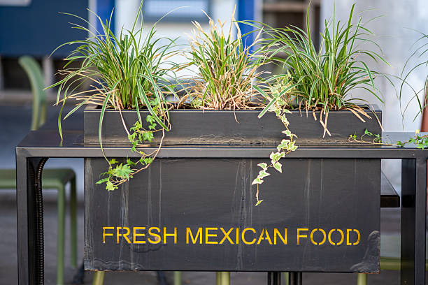 Yellow text reads fresh mexican food on outdoor planter box in background cafe setting