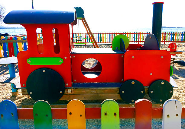 Children playground in the shape of  train locomotive  in the sunlight,  outdoor play equipment, jungle gym, slide by Compostela beach, seascape in the background. Vilagarcía de Arousa, Pontevedra province, Galicia, Spain.