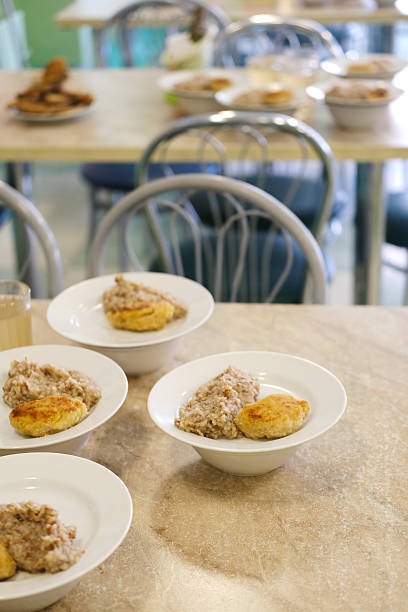 Bowls of hearty oatmeal and biscuits are arranged on a dining table in a cozy cafeteria setting, showcasing a warm and inviting breakfast atmosphere
