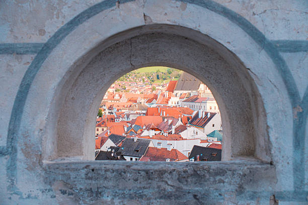 A fairy-tale landscape of the historic village, showcasing a dense tapestry of classic terracotta roofs and medieval bohemian architecture. The atmosphere is peaceful and sunny, emphasizing the timeless charm and romantic essence of a European heritage site.