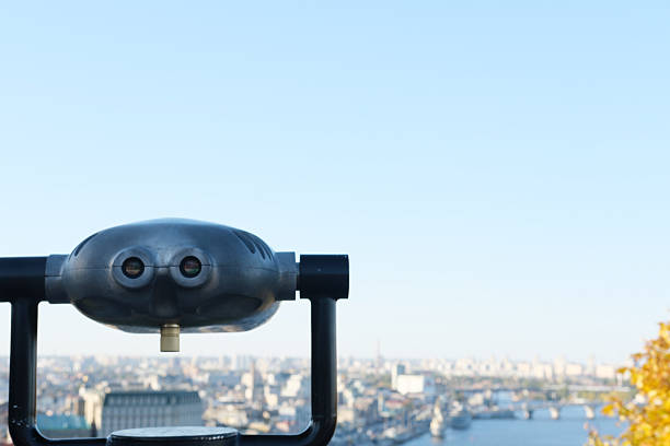Observation deck features binoculars providing stunning views of the city, highlighting urban structures, waterways, and a bright sky, creating an inviting atmosphere for exploration