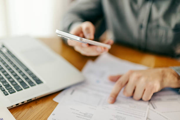 istock Man paying bills with smartphone and laptop 2260234342