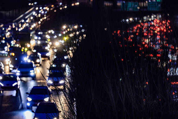 Nighttime traffic moving along a city highway with glowing headlights, capturing urban movement and modern city life.