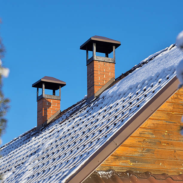 A chimney pipe on the cap. A winter house roof. Belarusian village