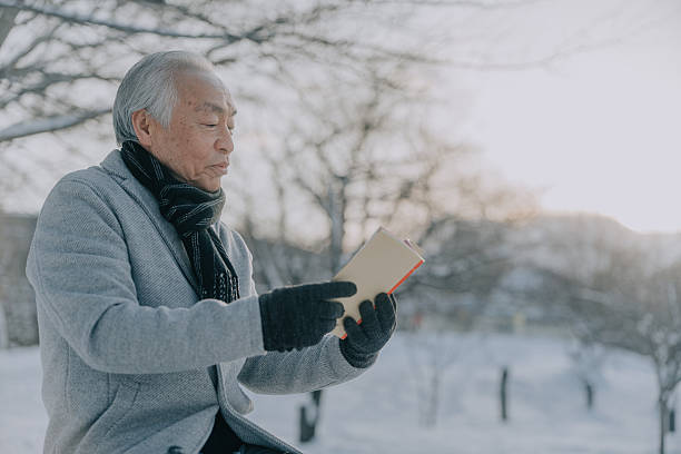 japanese senior man in calm reflection while reading in soft winter sunlight, Sapporo