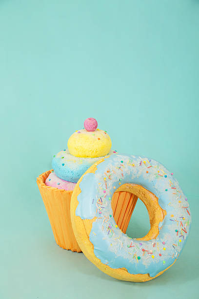 Artificial sweets made from polystyrene foam, featuring a colorful cupcake and a donut with blue icing and sprinkles, set against a light blue background