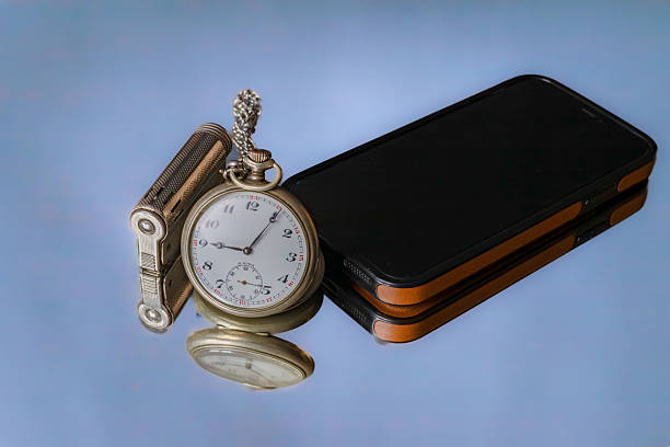 A reflective photograph where antique items from bygone eras—a pocket watch and a gas lighter—are displayed alongside a mobile phone, a symbol of modernity, on a mirror surface, reflecting the spirit of time.