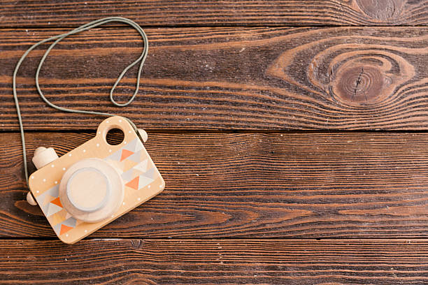 Wooden toy camera designed for children, showcasing colorful geometric patterns on a rustic wooden surface, with a cord attached for easy handling