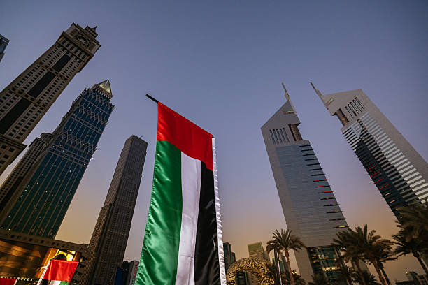 istock Modern skyscrapers illuminated at dusk in DIFC Dubai, showcasing contemporary architecture amidst palm trees and city flags 2260253832